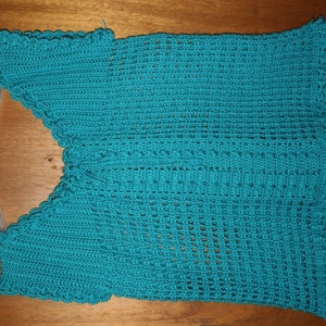 May include: Teal crochet top with a scalloped neckline and sleeves. The top is made with a delicate open stitch pattern.