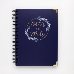 Puede incluir: Un cuaderno de espiral azul marino con una corona floral dorada y el texto "Cartas a mi Madre" en letras doradas.