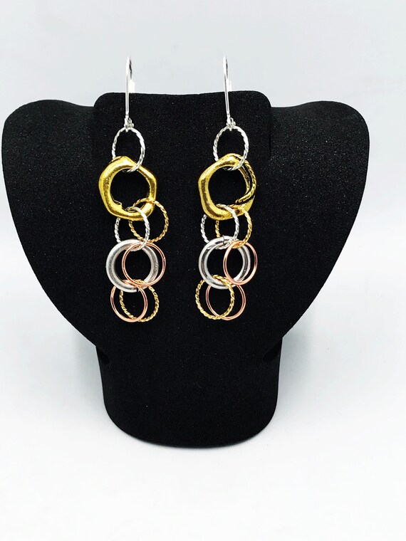 Silver, gold, and copper rings dangle earrings