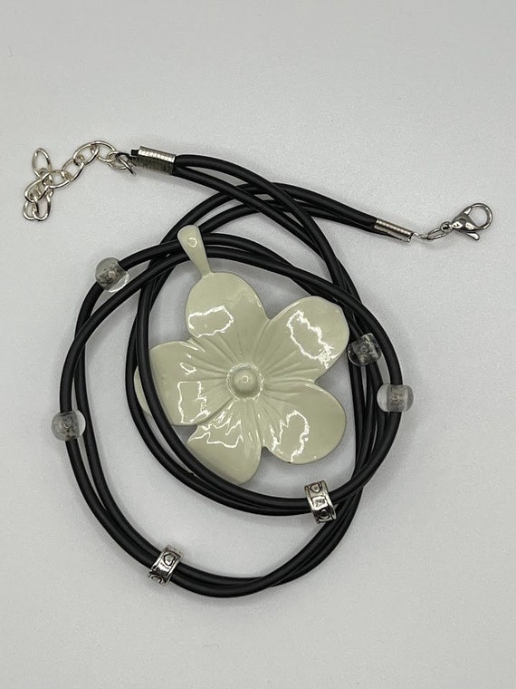 19" white metal flower pendant on black rubber cord with silver and clear bead accents