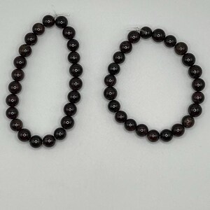 May include: A pair of large hoop earrings made of dark brown beads. The earrings are about 3 inches in diameter.