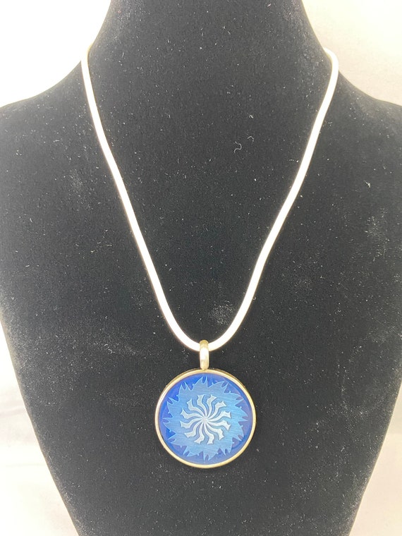 18" white or black rubber cord with pewter blue sun pendant