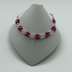 May include: A silver chain bracelet with pink and clear crystal flower beads.