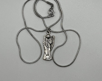 May include: A silver chain necklace with an angel pendant. The angel is holding a trumpet and has wings.