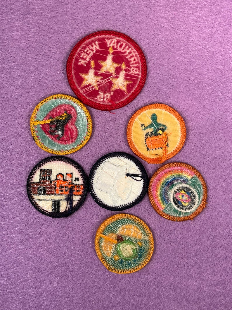 Puede incluir: Siete parches bordados con varios dise&ntilde;os, que incluyen un pastel de cumplea&ntilde;os, un coraz&oacute;n, un arco&iacute;ris, un edificio y una campana. Los parches son todos circulares y tienen un borde amarillo, naranja o rojo.