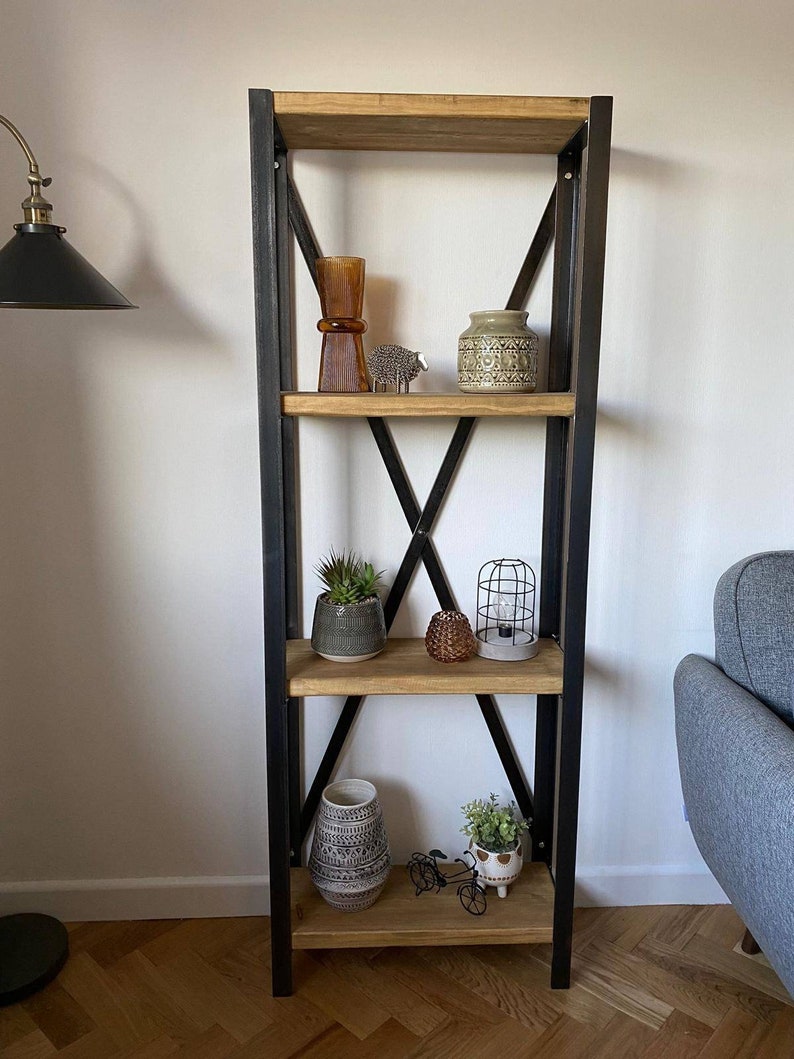 May include: A black metal shelf unit with four wooden shelves. The shelves are decorated with various items, including a vase, a potted plant, a small lamp, and a few decorative objects.