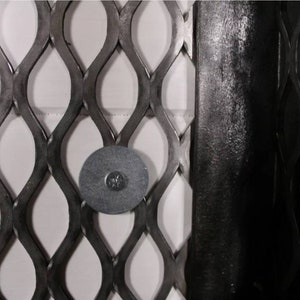 May include: Close-up of a black metal mesh with a round, black metal disc attached to it.