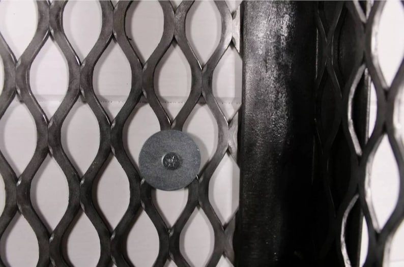 May include: Close-up of a black metal mesh with a round, black metal disc attached to it.