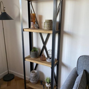 May include: A black metal shelf unit with four wooden shelves. The shelves are decorated with various items, including a vase, a lamp, and a potted plant.