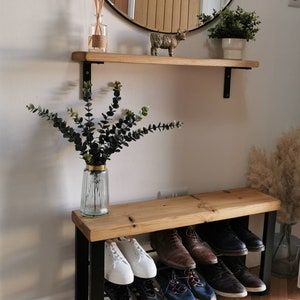 Puede incluir: Un banco de madera con un marco de metal negro y dos estantes para guardar zapatos. El banco est&aacute; hecho de madera natural y tiene un aspecto r&uacute;stico. Los estantes son robustos y pueden soportar mucho peso. El banco es perfecto para cualquier entrada o mudroom.