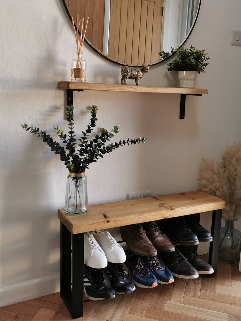 Puede incluir: Un banco de madera con un marco de metal negro y dos estantes para guardar zapatos. El banco est&aacute; hecho de madera natural y tiene un aspecto r&uacute;stico. Los estantes son robustos y pueden soportar mucho peso. El banco es perfecto para cualquier entrada o mudroom.
