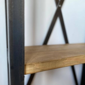 May include: Close-up of a wooden shelf with a dark brown metal frame. The shelf is made of natural wood with a light brown finish.