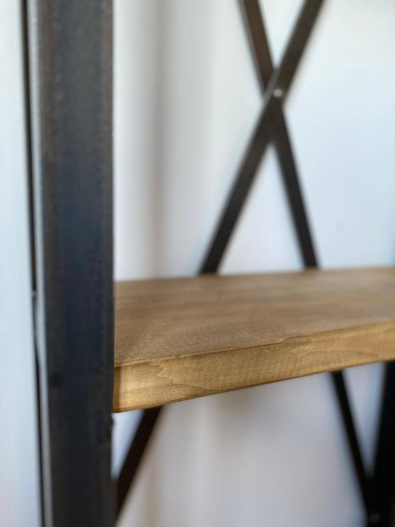 May include: Close-up of a wooden shelf with a dark brown metal frame. The shelf is made of natural wood with a light brown finish.