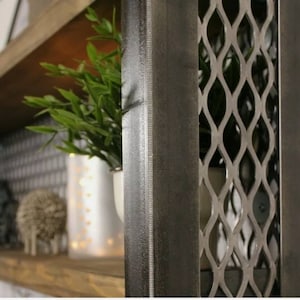 May include: A close-up of a dark gray metal shelf unit with a diamond-shaped wire mesh front. The shelf is made of wood and has a rustic finish.
