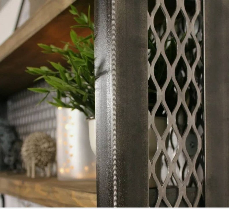 May include: A close-up of a dark gray metal shelf unit with a diamond-shaped wire mesh front. The shelf is made of wood and has a rustic finish.