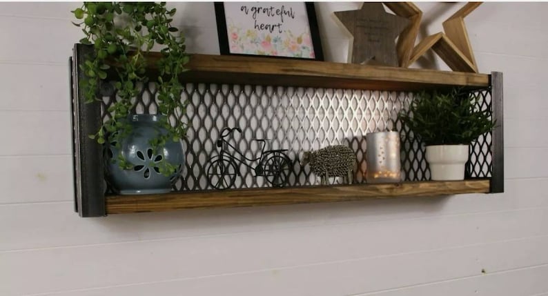 May include: A two-tiered wooden shelf with metal accents and a wire mesh back. The shelf is decorated with plants, a small bicycle figurine, and a silver metal sheep figurine. The top shelf has a framed print with the text "a grateful heart".