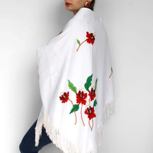 Klasyczny trójkątny szal z frędzlami i kwiatowymi zdobieniami, otulający ramiona