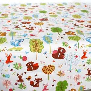 May include: A white fabric featuring a repeating pattern of brown squirrels, orange foxes, blue raccoons, pink snails, and various stylized green and blue trees. The design includes small red berries, tiny flowers, and dragonflies scattered throughout.