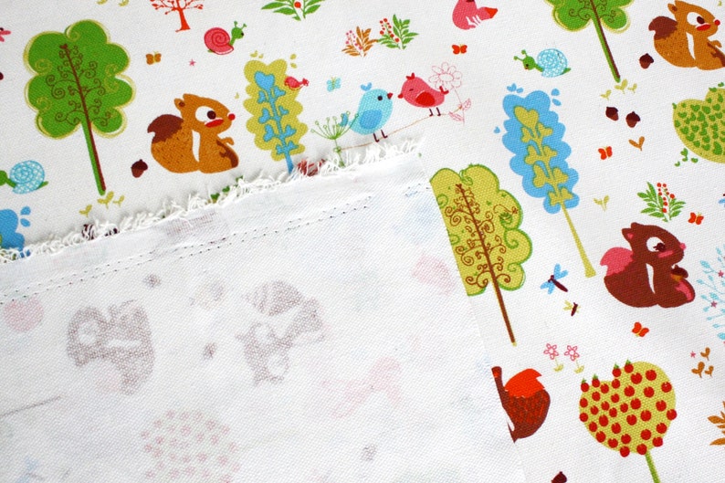 May include: A white fabric featuring a repeating pattern of brown squirrels, green and blue stylized trees, red and blue birds, snails, and small flowers. The fabric has a visible frayed edge and a stitched hem along the bottom section.