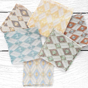 May include: A collection of six square fabric swatches arranged in a fan shape. Each swatch features a distinct diamond or geometric pattern in various colors including yellow, blue, green, orange, and brown on a light-colored background.