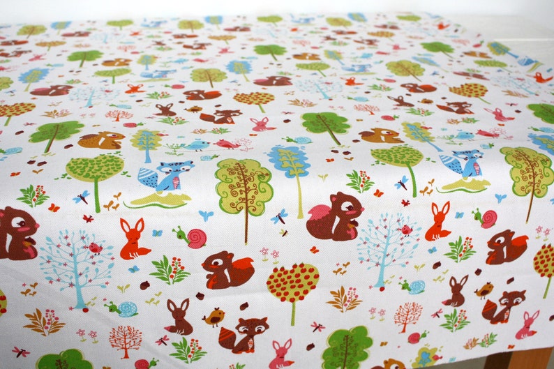 May include: A white fabric featuring a repeating pattern of woodland creatures including brown squirrels, orange foxes, and blue raccoons, interspersed with colorful stylized trees, small snails, birds, and various floral elements.