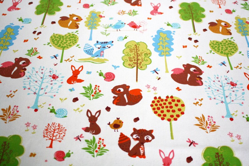 May include: A white fabric featuring a repeating pattern of woodland creatures including brown squirrels, orange foxes, and blue birds, interspersed with colorful stylized trees, green foliage, pink snails, and small red berries.