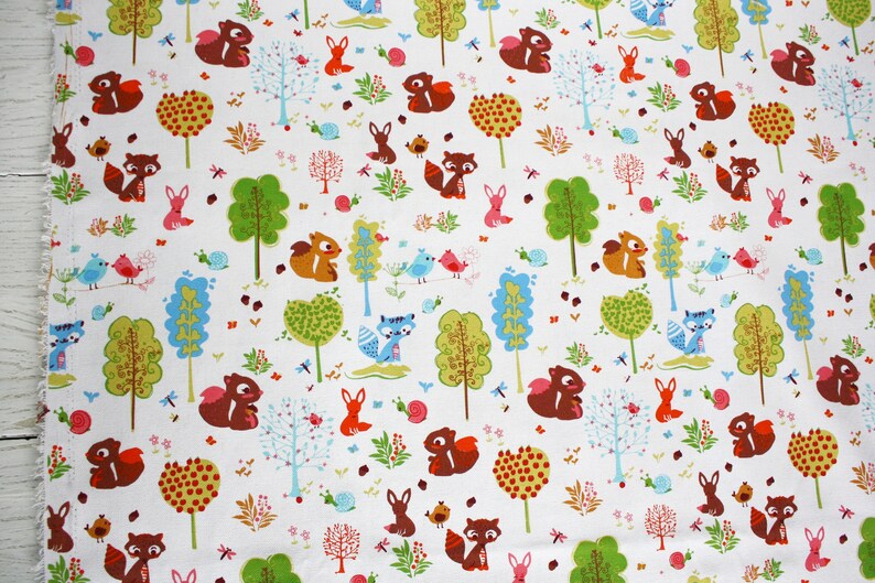 May include: A white fabric featuring a repeating pattern of brown squirrels, blue foxes, pink rabbits, and small birds. The design includes various stylized trees in shades of green and blue, along with small pink snails and tiny floral elements.