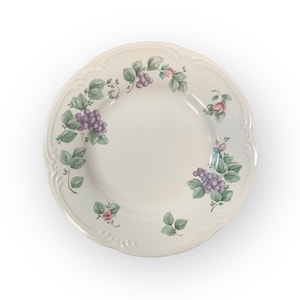 May include: A white ceramic dinner plate with a grapevine and floral design. The plate features purple grapes, green leaves, and pink roses.