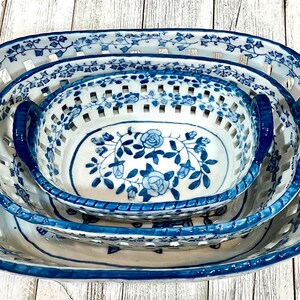May include: A set of three blue and white ceramic nesting bowls with handles. The bowls have a floral design and are made with a lattice pattern.