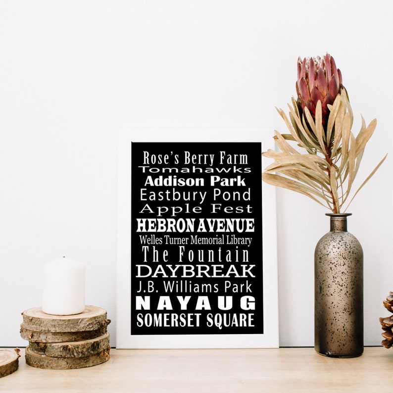 May include: Black and white typography print with the text "Rose's Berry Farm", "Tomahawks", "Addison Park", "Eastbury Pond", "Apple Fest", "HEBRON AVENUE", "Welles Turner Memorial Library", "The Fountain", "DAYBREAK", "J.B. Williams Park", "NAYAUG", and "SOMERSET SQUARE".