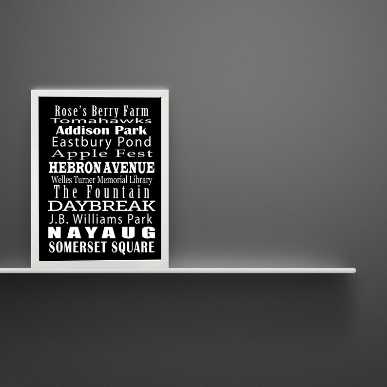 May include: Black and white framed print with a list of places and events in white text on a black background. The text includes: Rose's Berry Farm, Tomahawks, Addison Park, Eastbury Pond, Apple Fest, Hebron Avenue, Welles Turner Memorial Library, The Fountain, Daybreak, J.B. Williams Park, Nayaug, Somerset Square.