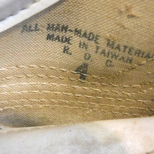 May include: Close-up of a white fabric shoe label with black text that reads "All Man-Made Materials Made in Taiwan R.O.C. 4".