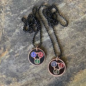 Colgante de cobre grabado a doble cara con quarks en neutrones y protones