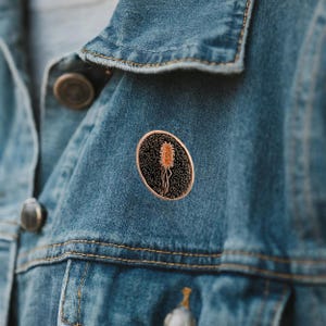 Pin de solapa o prendedor de corbata coloreado y grabado con E. coli