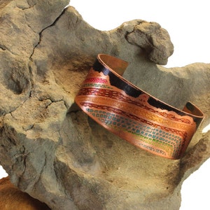 May include: A copper bracelet featuring a colourful geometric design. The bracelet is decorated with red, orange, yellow, green, blue and black enamel.