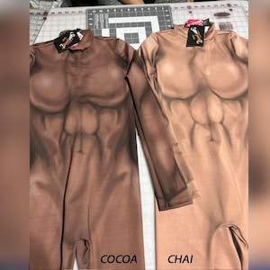 May include: Two long-sleeved bodysuits featuring a printed muscular torso design. The left bodysuit is a dark brown shade labeled COCOA, and the right bodysuit is a light tan shade labeled CHAI. Both garments have a mock neck and black tags.
