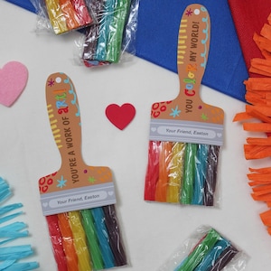 May include: Colorful rainbow-colored candy sticks packaged in clear plastic, arranged in the shape of a paintbrush. The paintbrush-shaped card reads "YOU'RE A WORK OF ART!" and "YOU COLOR MY WORLD!" with the text "Your Friend, Easton".