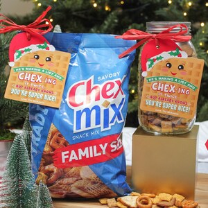 May include: A Christmas-themed gift idea featuring a jar of Chex Mix with a festive tag that reads "He's making a list and Chex-ing it twice, but already knows you're super nice!" The jar is sitting on a gold surface with a small artificial Christmas tree beside it. A bag of Chex Mix is in the background.