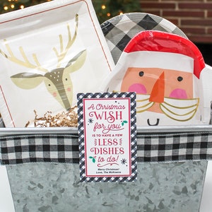 May include: A metal container with a black and white checkered ribbon around the top. Inside the container are paper plates with a reindeer and Santa Claus design. A gift tag with the text "A Christmas Wish for you is to have a few less dishes to do! Merry Christmas! Love, The McKeown" is attached to the container.