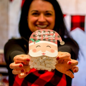 May include: A red and black checked Santa Claus face with the text "Believe in the Beard" and a white beard filled with white marshmallows.