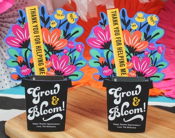 May include: Two black flower pots with a colorful floral design and the text "Grow & Bloom!"  The pots have a yellow ruler with the text "Thank you for helping me".