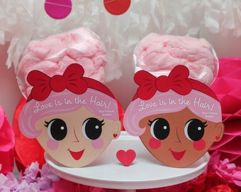 May include: Two pink cotton candy favours with red bows and a cartoon face on the front. The faces have the text "Love is in the Hair!" and "Your Friend Exstor".