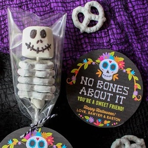 May include: Two Halloween treat bags with pretzel skeletons and marshmallow heads. Each bag has a black and white tag with a colorful skull and the text "No Bones About It You're a Sweet Friend! Happy Halloween! Love, Sawyer & Easton."
