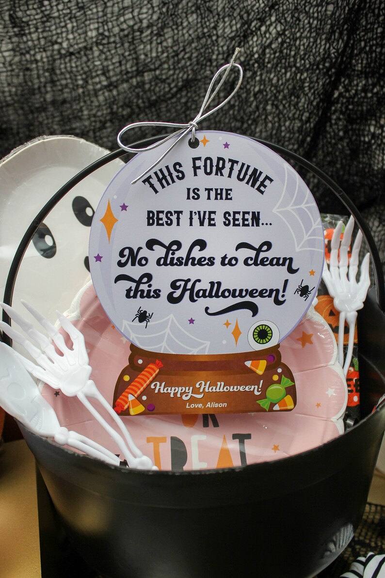 May include: A black cauldron filled with Halloween treats, including pink paper plates with a skeleton hand design, white plastic skeleton hand forks, and a fortune cookie with the text "THIS FORTUNE IS THE BEST I'VE SEEN... No dishes to clean this Halloween! Happy Halloween! Love, Alison."