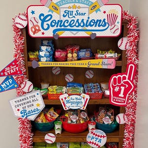 May include: A wooden display shelf filled with snacks and drinks, decorated with baseball-themed accents. The top sign reads "All Star Concessions" and "Teacher & Staff." Other signs say "Thanks for making this year a Grand Slam!" and "Ice Cold Beverages."