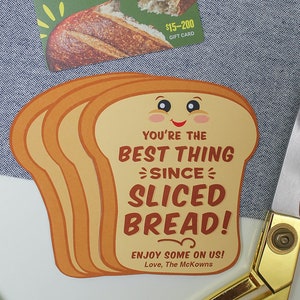 May include: A brown and yellow card shaped like a slice of bread with the text "You're the best thing since sliced bread!" and "Enjoy some on us! Love, The McKowns".