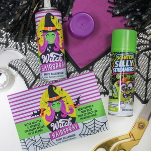 May include: Two green and white cans of hairspray with a witch cartoon on the front. The cans are labeled "Witch Hairspray" and "Scented Silly Streamers". The cans are on a white surface with black and white lace, purple fabric, and gold scissors.