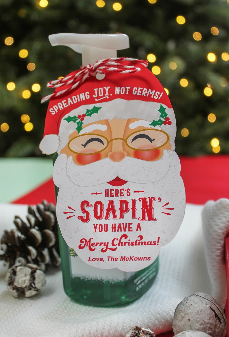 Op de afbeelding: Een groene vloeibare handzeepfles met een rood-witte kerstman-thema cadeau-etiket met de tekst "Spreading Joy, Not Germs!" en "Here's Soapin' You Have a Merry Christmas! Love, The McKowns".