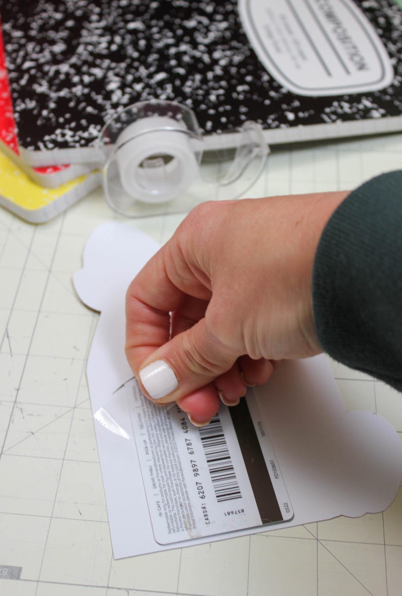 May include: A white gift card with a black barcode and the text "CARD#: 6207 9897 6787 4084" on the back. The card is being peeled off of a white paper backing.