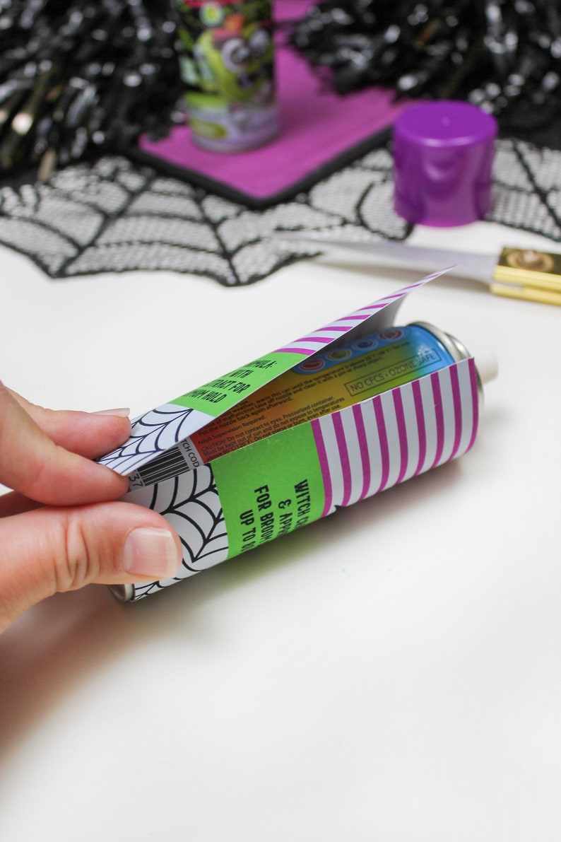 May include: A green and purple can with a spiderweb design and the text "Witch's Brew & Apple Cider" and "For Brooding Up To 14 Days". The can is partially covered with a pink and white striped paper.